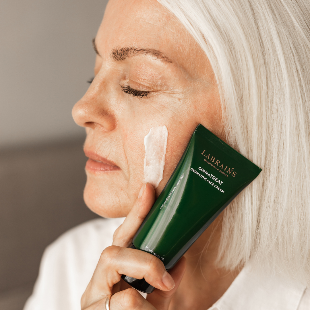 woman holding labrains dermatreat cream next to her face