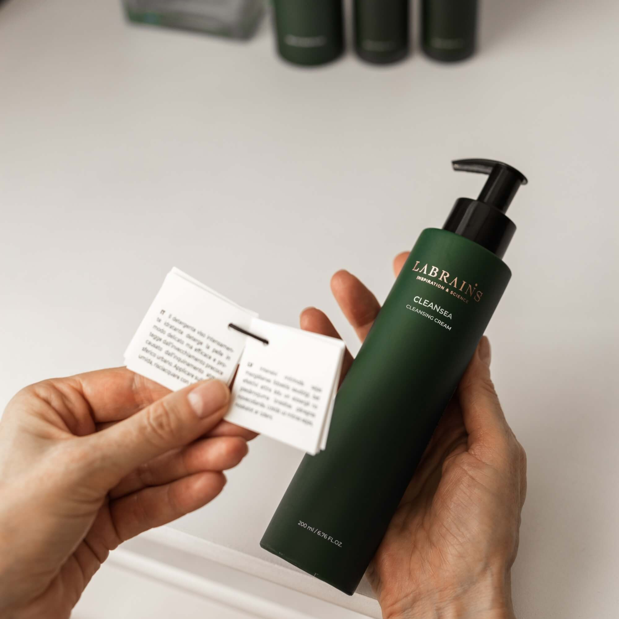 Person holding LABRAINS cleansing cream and a card on white background