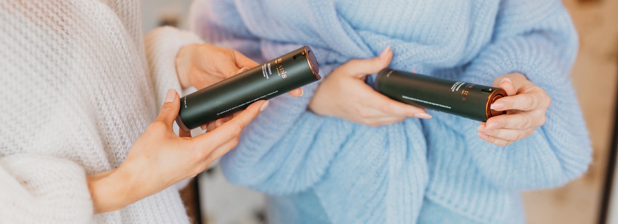 Two women holding labrains skincare products in a cozy setting.