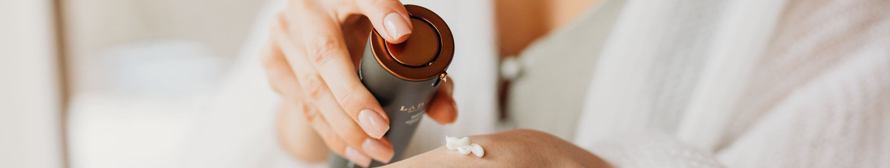 woman in white applying labrains cream to her hand with a focus on skincare routine.