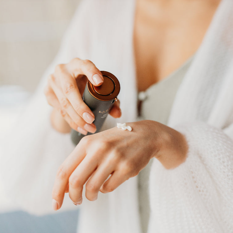 woman in white applying labrains cream to her hand with a focus on skincare routine.