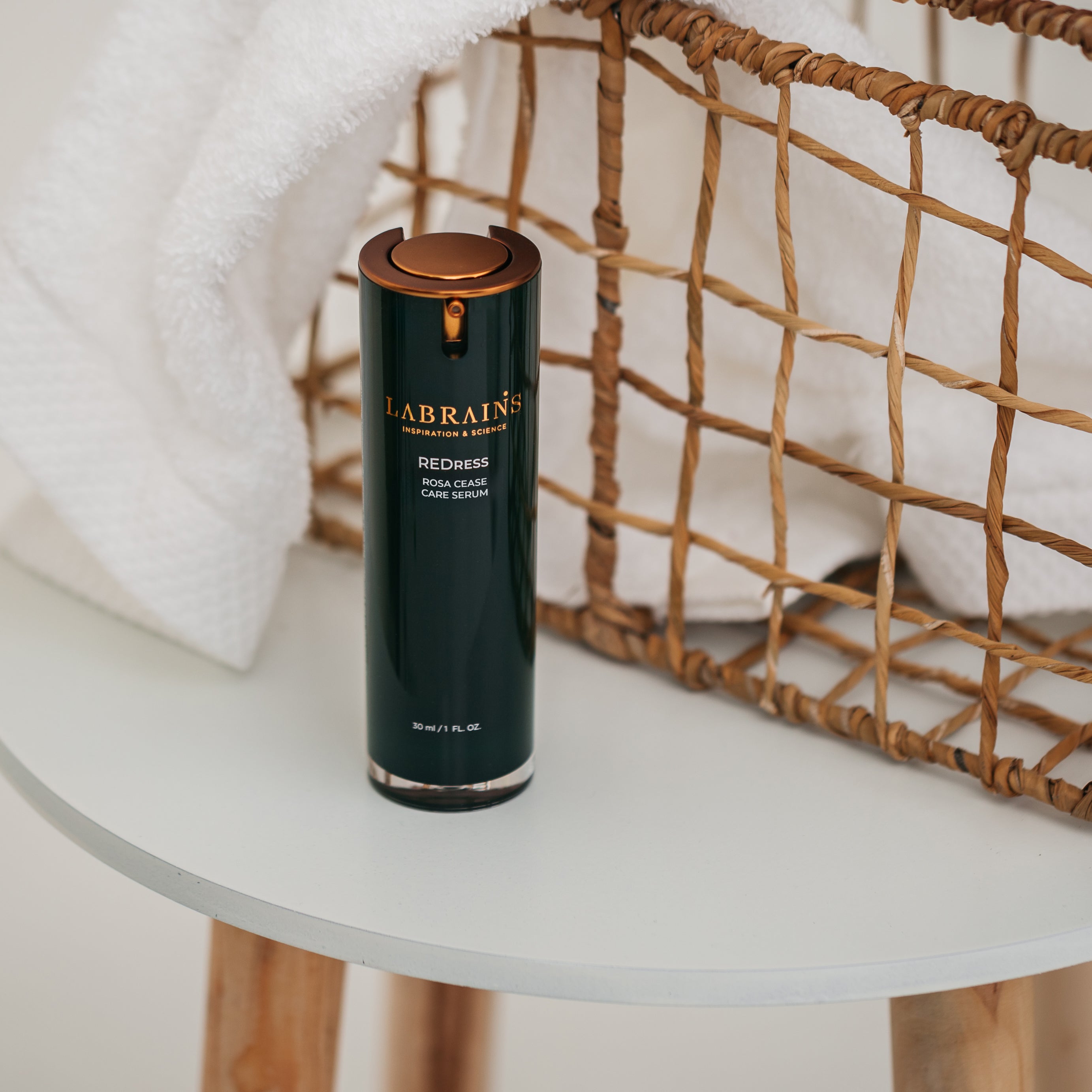 Labrains skincare rosa cease care serum bottle on a white surface with a woven basket in the background