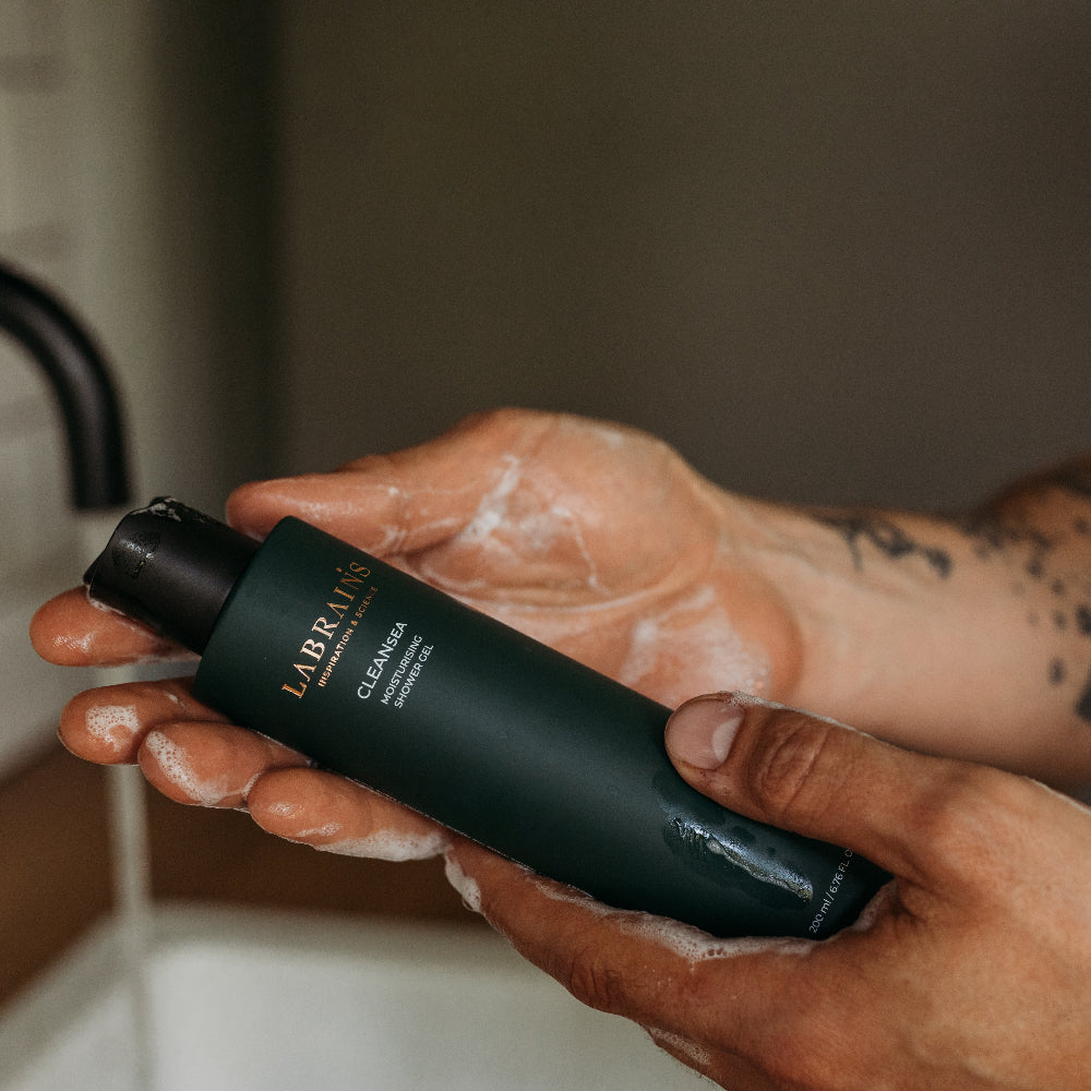 Man holding a Labrains shower gel bottle in a bathroom setting