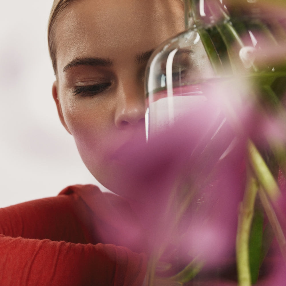 Woman wearing a red sweater, surrounded by pink flowers.