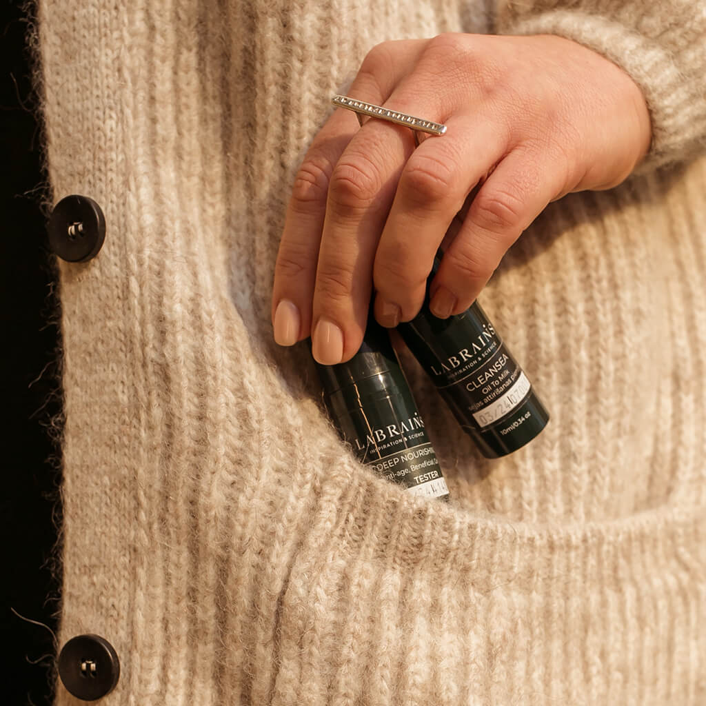 woman holding two labrains travel size products near her pocket