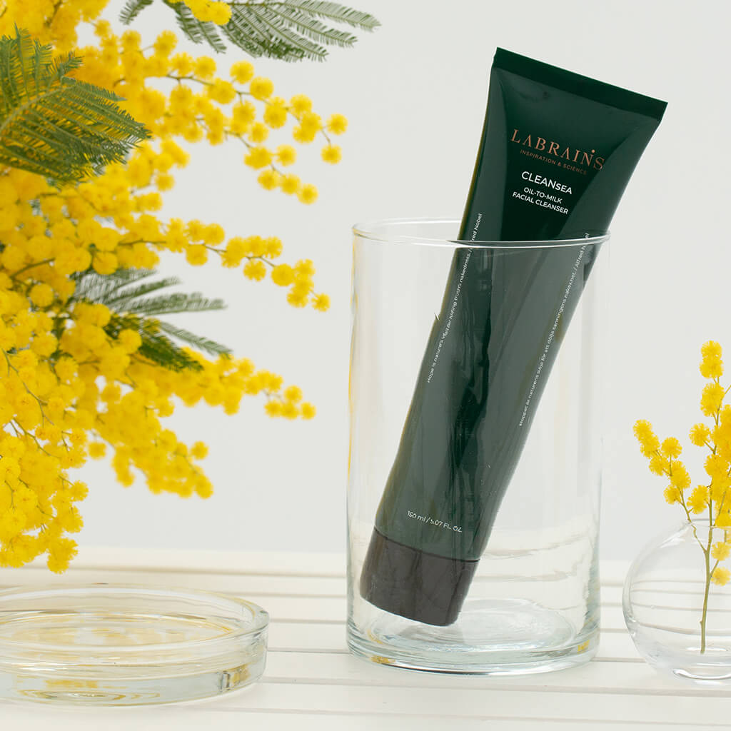 labrains oil-to-milk cleanser in a glass with sedum flowers in the background
